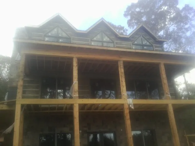 Dormers and porch framing on a large log home under construction — Roof Coating work by our crew in Horicon