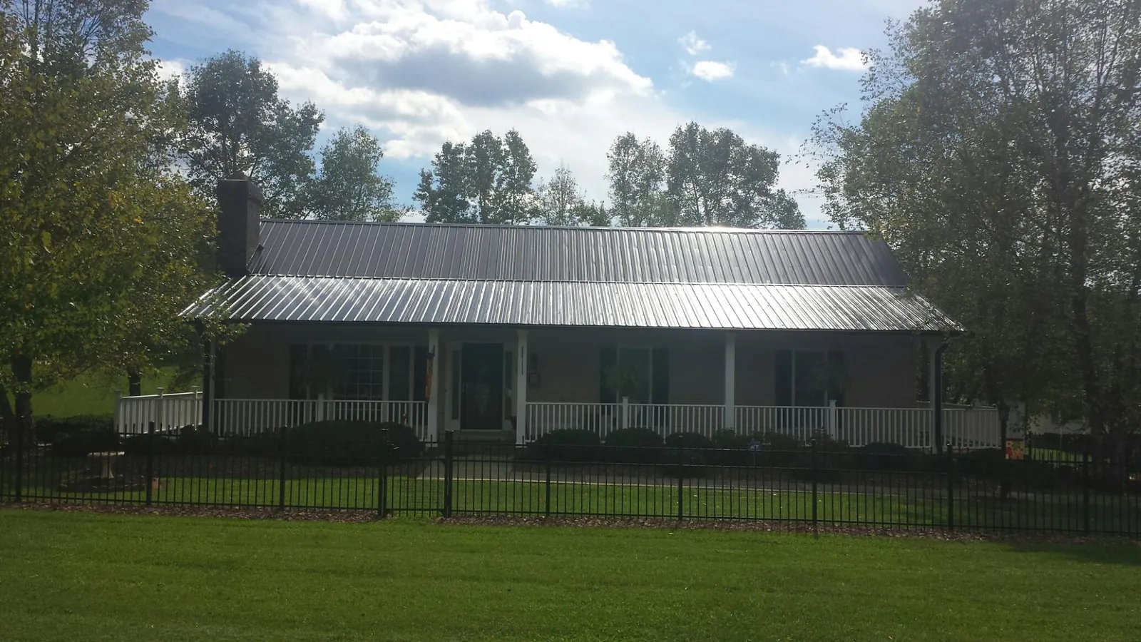 Gray metal roof on a brick ranch with a full width front porch — Gutter Guard Installation work by our crew in Horicon